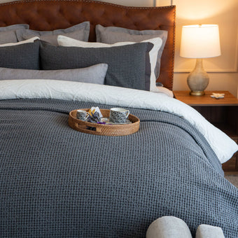 Quilt tipo waffle color gris sobre cama, ideal para capas ligeras