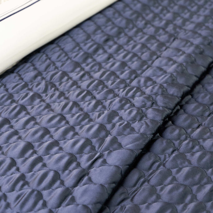 Quilt de satín color perla sobre cama, estilo elegante y brillante