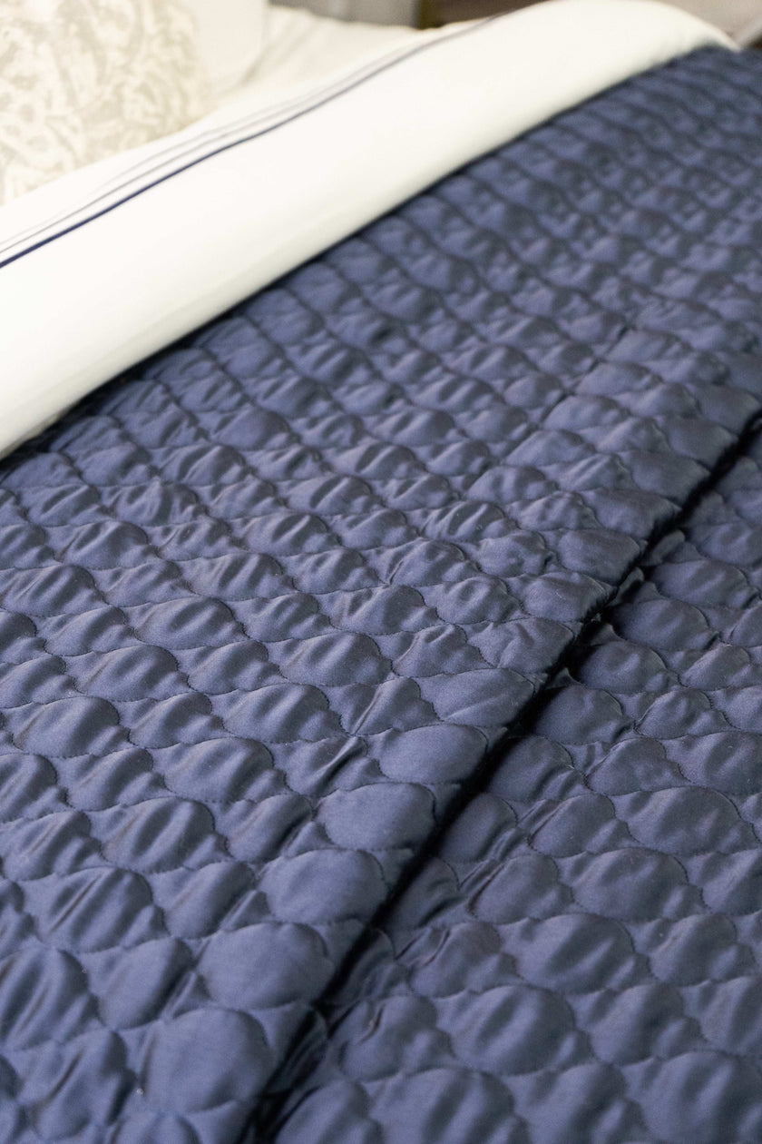 Quilt de satín color perla sobre cama, estilo elegante y brillante