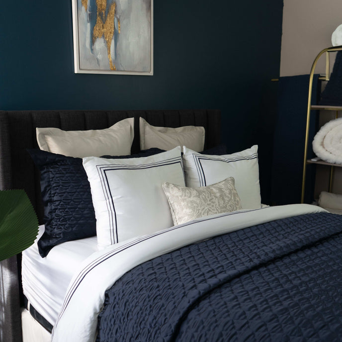 Quilt de satín color navy sobre cama, estilo elegante y brillante
