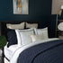 Quilt de satín color navy sobre cama, estilo elegante y brillante
