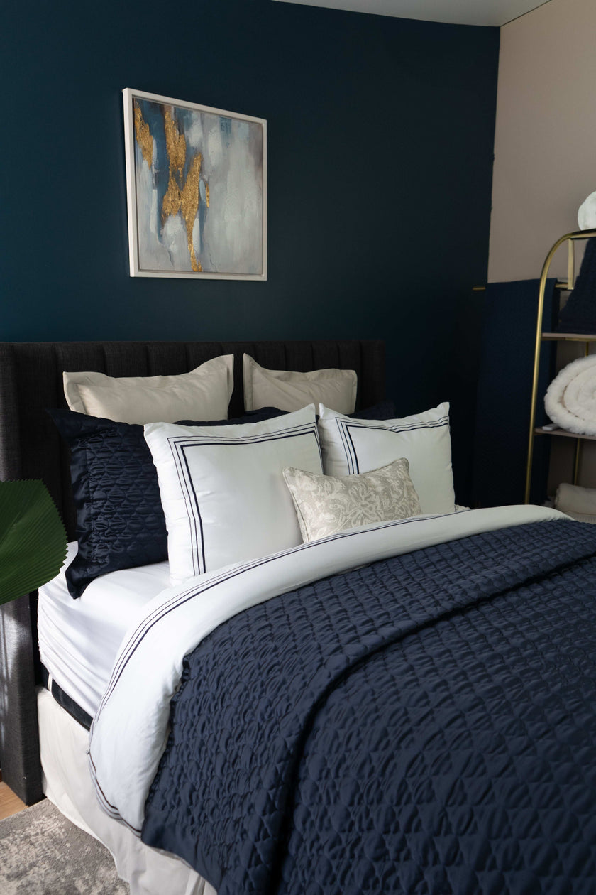 Quilt de satín color navy sobre cama, estilo elegante y brillante
