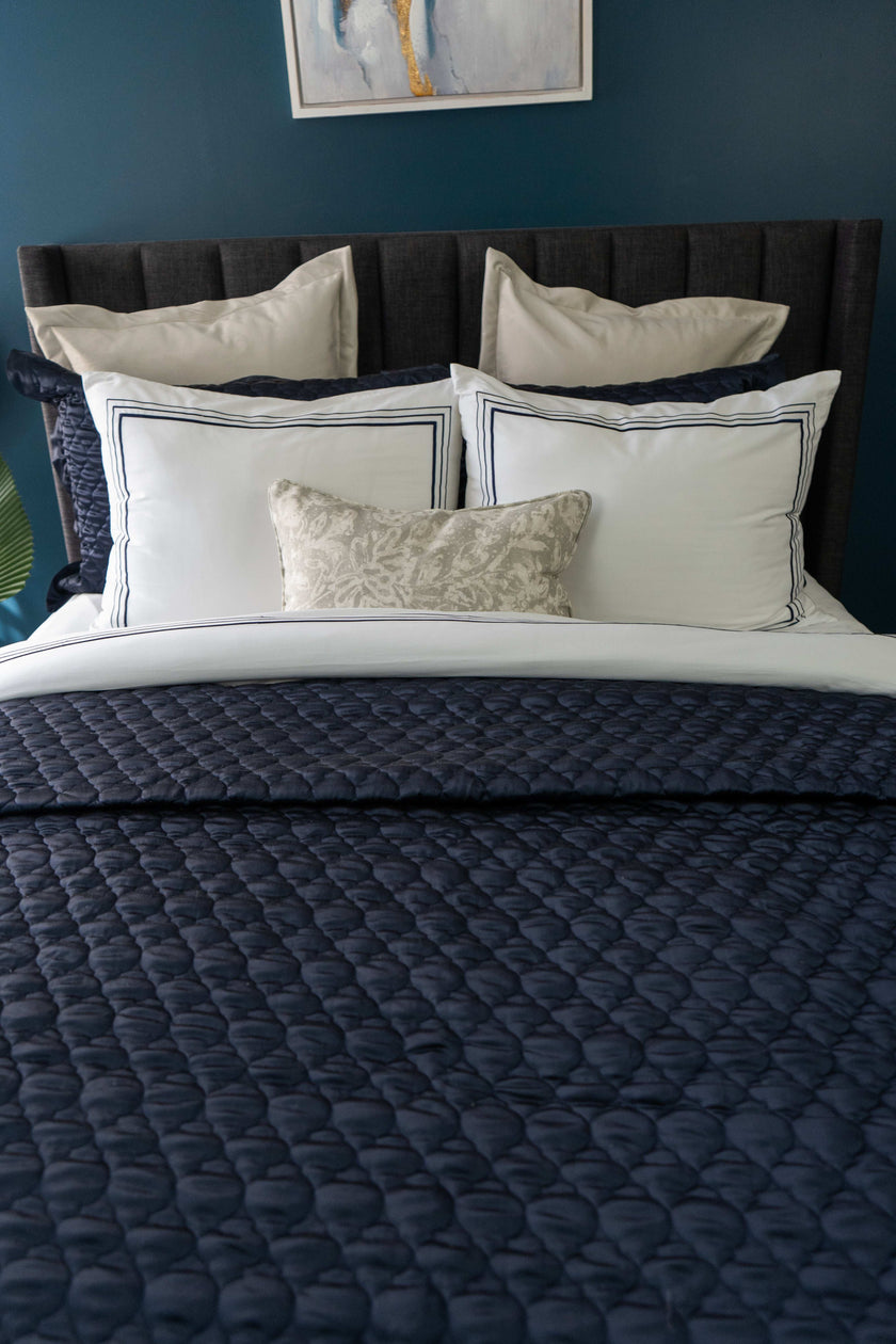 Quilt de satín color perla sobre cama, estilo elegante y brillante

